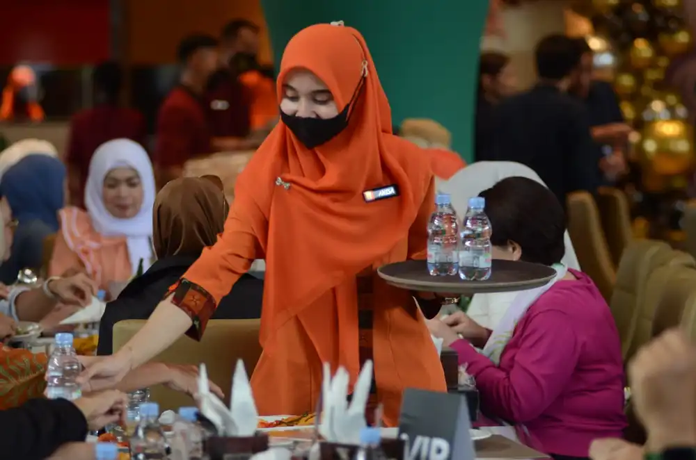 Pramusaji Restoran Padang Pagi Sore sedang menyajikan minuman kepada tamu undangan