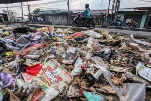 Pengendara melintasi tumpukan sampah yang menumpuk di pinggir jalan raya (1)