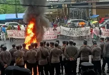 Massa dari berbagai elemen masyarakat melakukan aksi unjuk rasa menolak rapat pleno penetapan pemenang pilkada oleh KPU Kota Tasikmalaya di depan Hotel Grand Metro Tasikmalaya (Foto: Kompas)