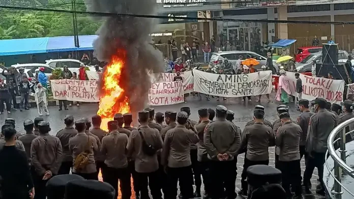 Massa dari berbagai elemen masyarakat melakukan aksi unjuk rasa menolak rapat pleno penetapan pemenang pilkada oleh KPU Kota Tasikmalaya di depan Hotel Grand Metro Tasikmalaya (Foto: Kompas)