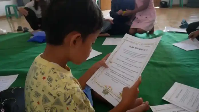 Seorang anak di Dago Elos Bandung me-review bahan bacaan, sebagai salah satu kegiatan TuturKami dalam meningkatkan literasi. (Foto: Ist)