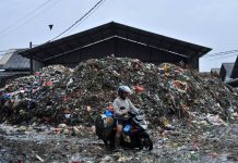 Pengendara melintasi di tumpukan sampah di kawasan Pasar Caringin (1)