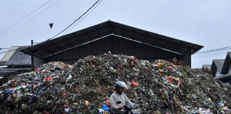 Pengendara melintasi di tumpukan sampah di kawasan Pasar Caringin (1)