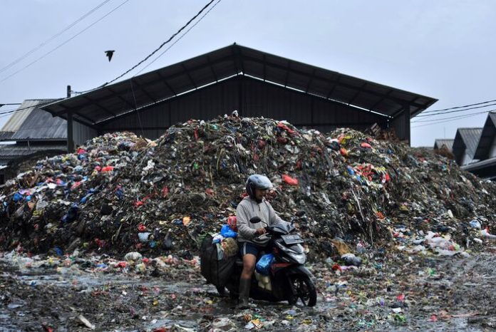 Pengendara melintasi di tumpukan sampah di kawasan Pasar Caringin (1)